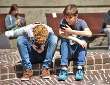 2 boys sitting on sidewalk